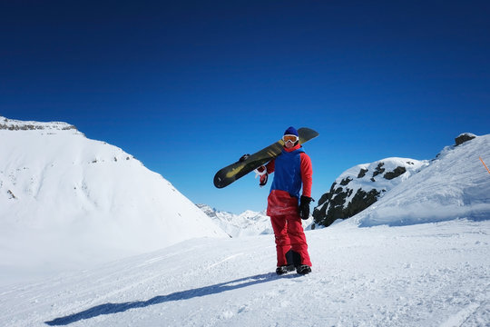 male sportsman snowboarder stands against the background of mountains