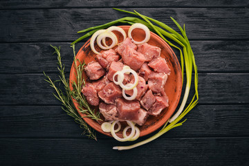 Raw meat is cooked for shish kebab on a wooden background. On the plate Top view. Free space for text.