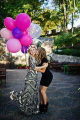 Two girls wear on black with balloons at hen party.