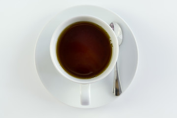 Top view close up of a cup of black tea, on white table