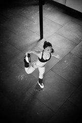 Girl is stretching leg standing, b&w