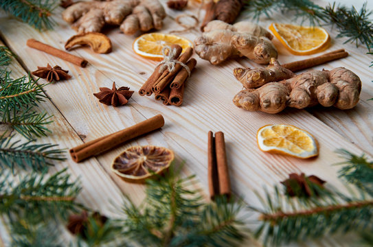 Cinnamon sticks with anise stars, ginger, dried oranges on the wooden background with Christmas tree branches still life. Christmas background composition with new year decorations. Flat lay