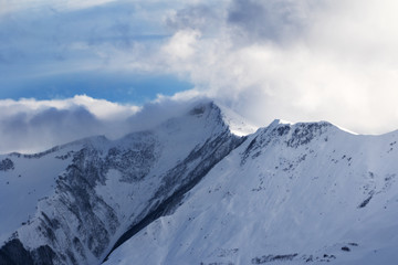 Snowy off-piste slope and sunlight mountains in haze