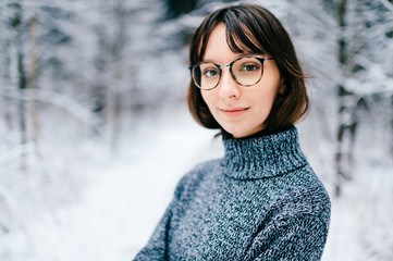 Beautiful positive fashionable stylish modern brunette girl in trendy glasses looking at camera. Cute lovely teenager person with tender kind simple face. Soft focus portrait. Woman with snow on hair.