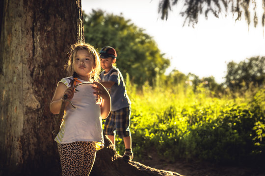 Cute charming plumpy girl playing outdoors in woodland during summer holidays symbolizing happy carefree childhood in countryside