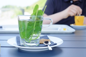 Green herbal tea with fresh mint leaves on a saucer with a spoon