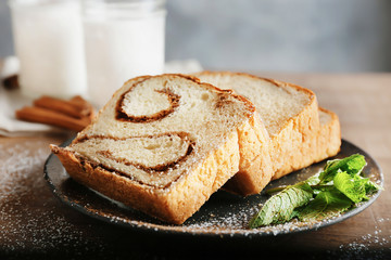 Plate with delicious cinnamon roll cake on table