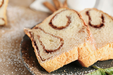 Plate with delicious cinnamon roll cake on table