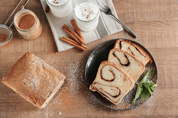 Plate with delicious cinnamon roll cake on table