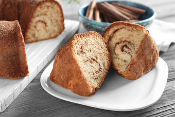 Plate with delicious cinnamon roll cake on table