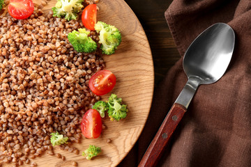 Plate with tasty buckwheat porridge and vegetables on table, closeup