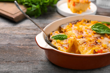 Baking dish with corn pudding on wooden table, closeup