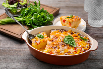 Baking dish with corn pudding on wooden table