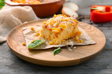 Plate with piece of corn pudding on wooden table