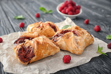 Parchment with delicious puff pastries on wooden table