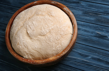 Bowl with fresh raw dough on wooden table