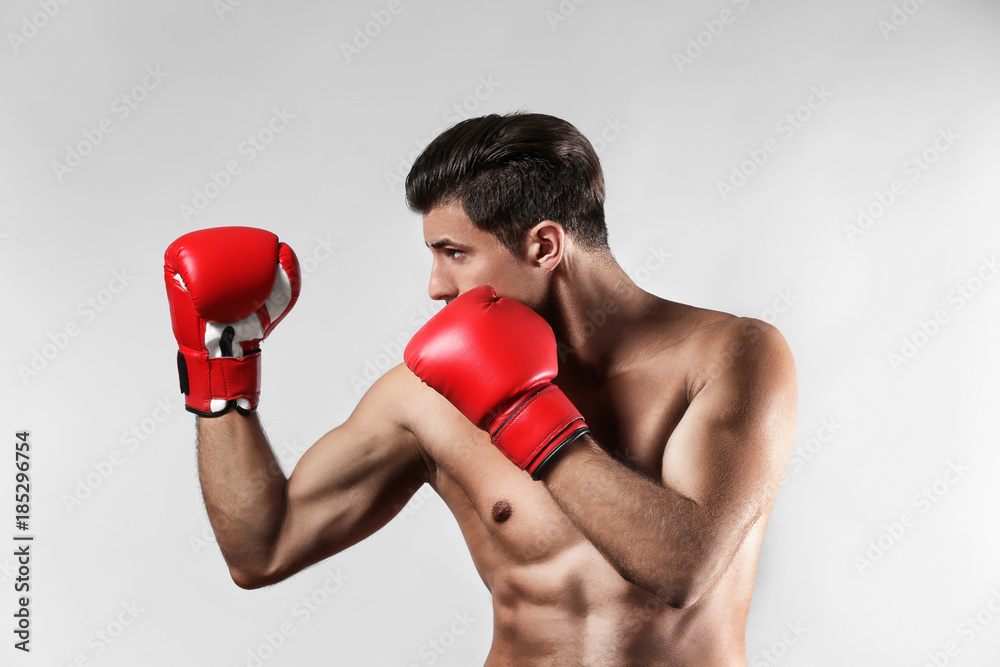 Wall mural attractive young boxer on light background