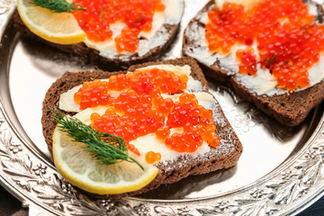Tin can with delicious red caviar, dill and sandwich on table