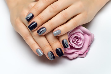 Obraz na płótnie Canvas Delicate gray blue manicure with drops and silver on long square nails with rose in hand