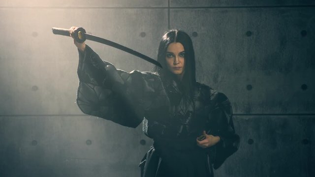 Martial arts Concept. Woman in kimono practicing with katana