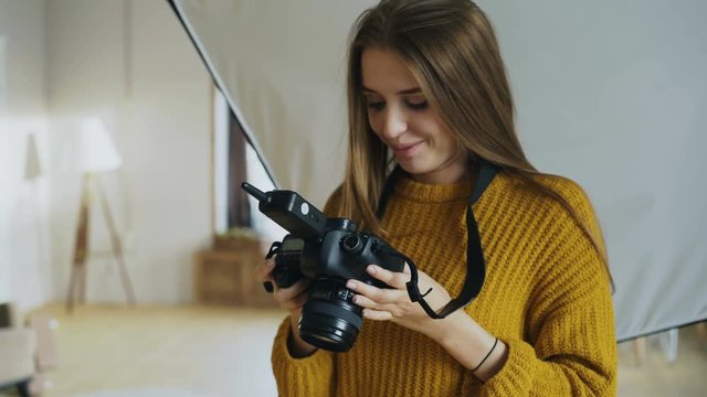Young woman photographer working in a photo studio taking photos of male model on digital camera