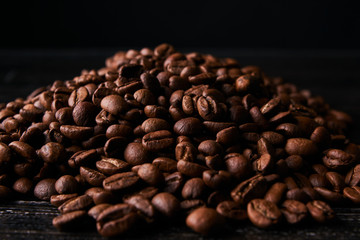Heap of roasted coffee beans on dark background, close-up. 
