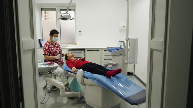 Dentist examining a teeth of little girl. Dentist using a mirror and dental proba. A dentist and little girl are dressed at clothes in the New Year's theme. Camera movement