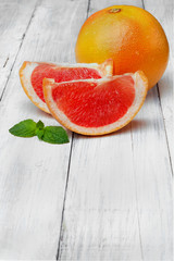 Whole grapefruit and two slices with leaf of mint.On white woode