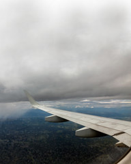 Fototapeta na wymiar Airplane trip view of one of the wing between cloudy sky and ground