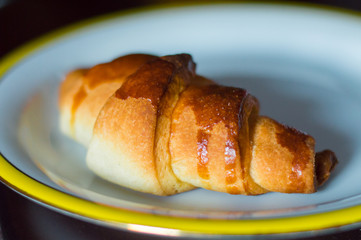 Homemade croissant on white plate.