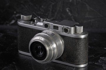 Fototapeta na wymiar Old rangefinder film camera on a black concrete background.