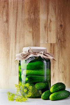 Jar with cucumbers three cucumbers and flower of dill.Wooden background .Free space.Vertical shot