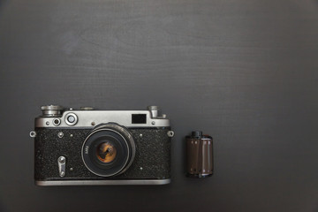 Vintage Film Camera And Roll On Black Wooden Background Technology Development Photographer Concept...