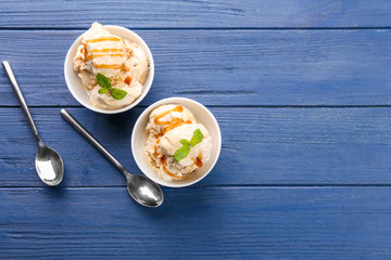 Delicious ice cream with caramel syrup in bowls on table