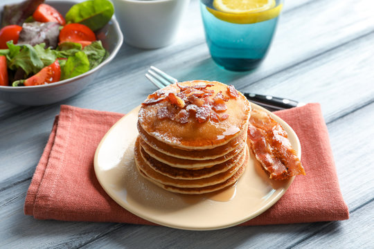 Tasty breakfast with pancakes and bacon on table