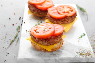 Delicious burgers with cheese and tomato on board