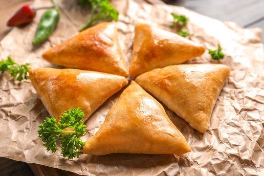 Delicious baked samosas on table