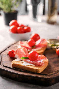Delicious sandwich with cherry tomato and salami on wooden board, closeup
