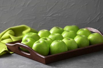 Tray with fresh green apples on grey background