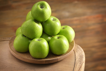 Fresh green apples on wooden plate