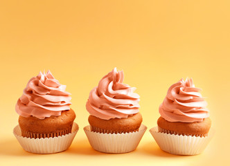 Tasty cupcakes on color background