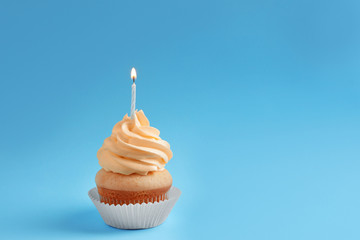 Tasty cupcake with candle on color background