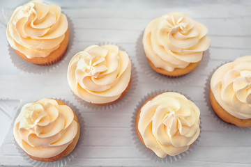 Tasty cupcakes on wooden board