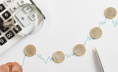 calculator and coin stack on the stock market paper