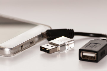 The smartphone next to which is usb flash memory and a cable for its connection to the smartphone.