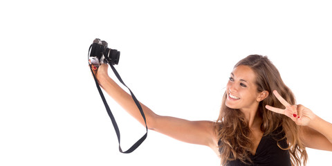 Pretty happy girl taking a selfie with a vintage camera; isolated on white, customizable background with copy space