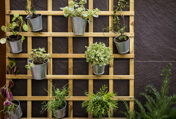 wooden grid on a wall made of stone with metallic flowerpots