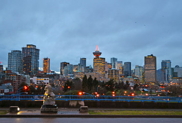 Fototapeta premium Vancouver, British Columbia, Canada, 2012. Skyline of the city from a wet street closed to the harbor at dusk lit by many artificial lights