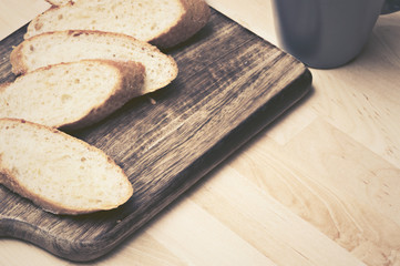 Sliced baguette bread on wooden plate with coffee