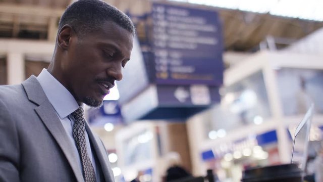 Business professional typing on his laptop as he is out and about 